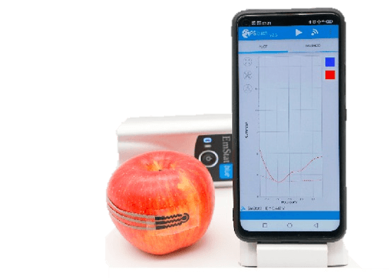Printed sensor attached to an apple beside a smartphone measurement display