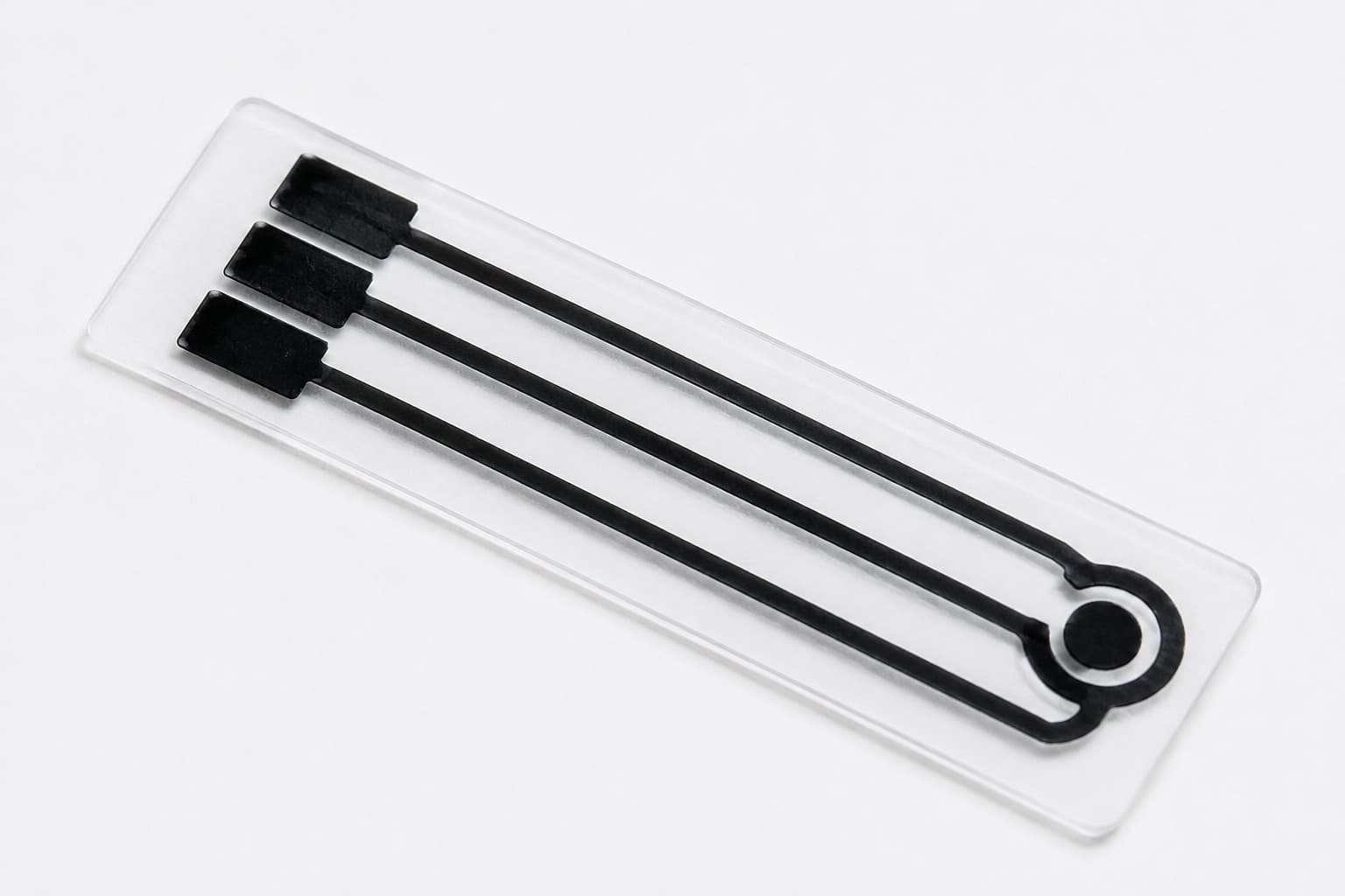 Close-up of a black printed three-electrode sensor on a transparent strip